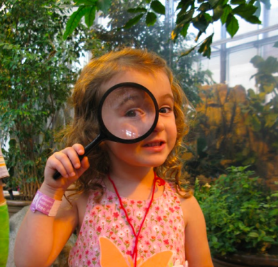 girl holding magnifying glass up to her eye