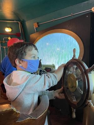 boy at helm of boat