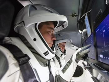 two astronauts touching a screen