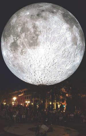 big moon over crowd of people at night