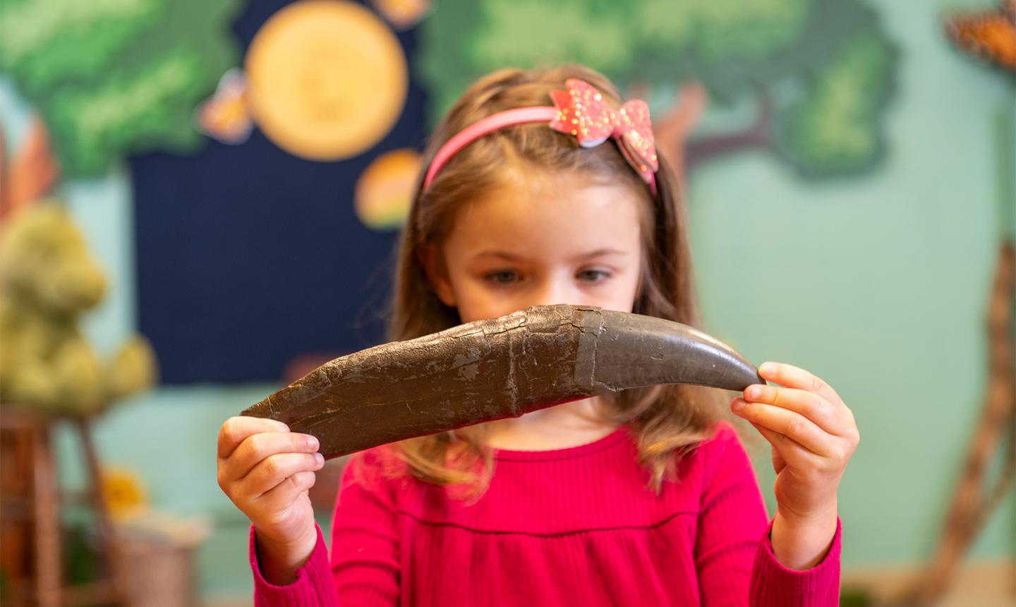 Young girl holding fossil like claw in front of her face